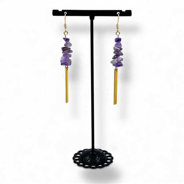 Pair of purple beaded earrings on a black stand against a white background