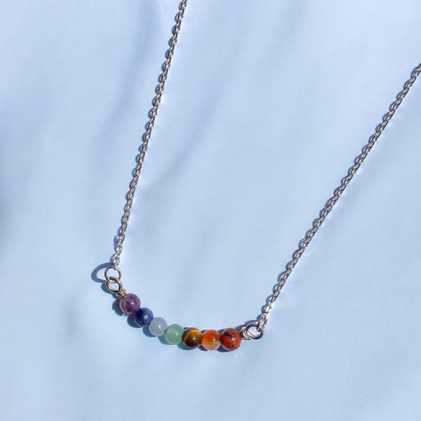 Silver stainless steel necklace with multicolored gemstones in a horizontal pendant for self love, pride, and spirituality.
