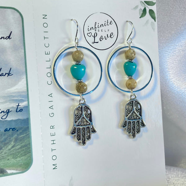 Silver gemstone earrings with hoops, hamsa symbol, turquoise magnesite heart and picture jasper beads. Earrings on a positive affirmation card with a channeled message from Mother Gaia using Light Language.