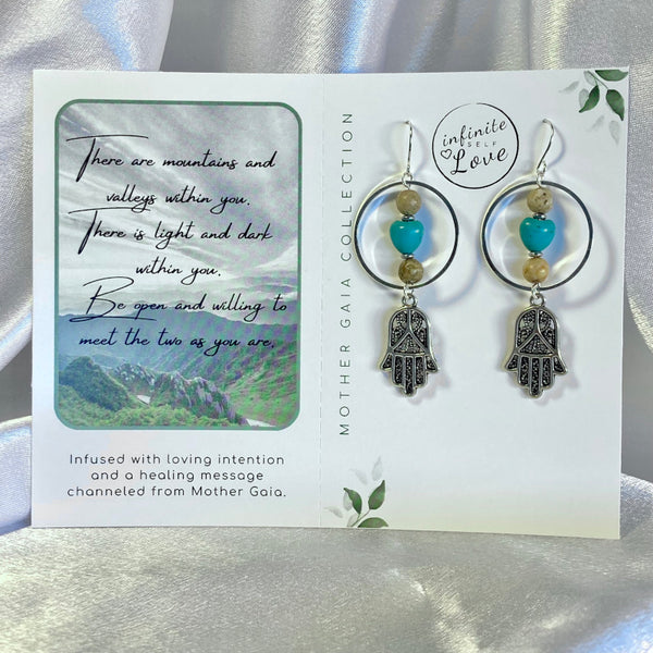 Silver gemstone earrings with hoops, hamsa symbol, turquoise magnesite heart and picture jasper beads. Earrings on a positive affirmation card with a channeled message from Mother Gaia using Light Language.